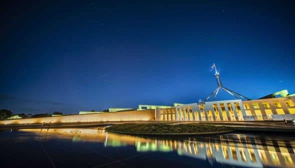 Night view of Parliament House in Canberra with reflections in the water. - Olive Oil Times