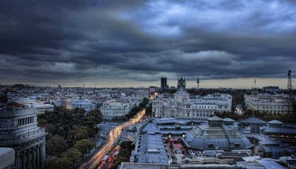 A panoramic view of Madrid's skyline during dusk with cloudy skies and city lights. - Olive Oil Times