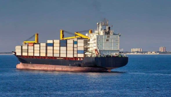 Large container ship with stacked cargo containers sailing in open water. - Olive Oil Times