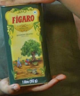 Person holding a green Figaro brand olive oil container with a tree illustration on the label. - Olive Oil Times