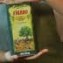 Person holding a green Figaro brand olive oil container with a tree illustration on the label. - Olive Oil Times