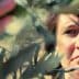 Woman closely examining olive tree leaves in a natural setting. - Olive Oil Times