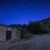 A stone building with a wooden door under a starry night sky with visible meteor trails. - Olive Oil Times