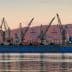 Cargo ship docked at the port of Volos with cranes and a tugboat nearby. - Olive Oil Times