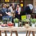 A table featuring various bottles of olive oil and fresh produce at an event. - Olive Oil Times