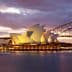 Sydney Opera House illuminated at sunset with the Harbour Bridge in the background. - Olive Oil Times