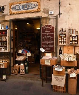 Entrance of a traditional Italian grocery store with various products displayed outside. - Olive Oil Times