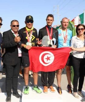 Group photo of Sfax Marathon winners holding a trophy and a Tunisian flag with event organizers. - Olive Oil Times