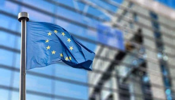 European Union flag with twelve stars on a blue background, waving in the wind. - Olive Oil Times