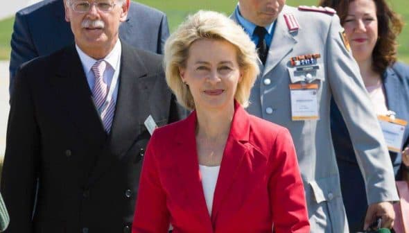 A group of officials, including a woman in a red suit, walking together at an outdoor event. - Olive Oil Times