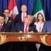 Political leaders signing the USMCA agreement at a table with flags of the US, Canada, and Mexico in the background. - Olive Oil Times