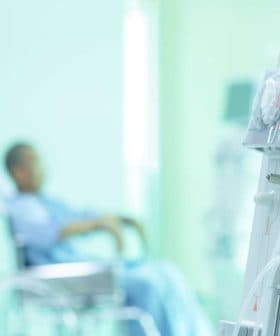 Dialysis machine with dials and tubes in a medical environment with a patient in a wheelchair in the background. - Olive Oil Times