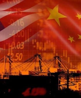 Overlay of the United States and China flags with shipping cranes and stock market graphics in the background. - Olive Oil Times