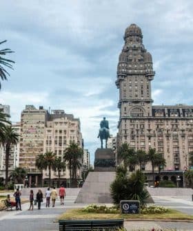 Statue of a horseman located in Plaza Independencia, surrounded by palm trees and buildings in Montevideo. - Olive Oil Times
