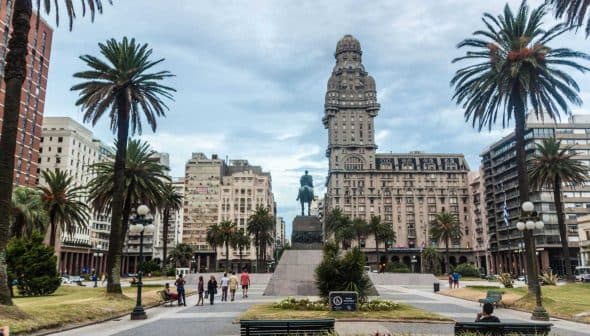 Statue of a horseman located in Plaza Independencia, surrounded by palm trees and buildings in Montevideo. - Olive Oil Times