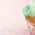 Three ice cream cones with green, pink, and yellow ice cream topped with colorful sprinkles. - Olive Oil Times