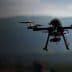 A quadcopter drone flying in the air with a blurred background of mountains. - Olive Oil Times
