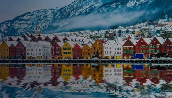 Row of colorful waterfront houses reflecting in the water in Bergen, Norway during winter. - Olive Oil Times