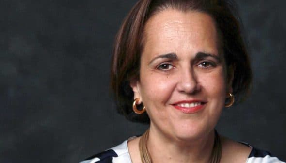 Portrait of a woman with short brown hair wearing hoop earrings and a striped top. - Olive Oil Times