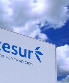 Signage displaying the Acesur logo and slogan against a blue sky with clouds. - Olive Oil Times