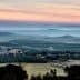 A panoramic view of a vineyard landscape with rolling hills and a colorful sky at dusk. - Olive Oil Times