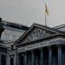 The Congreso de los Diputados building in Spain with a statue in front and a flag on top. - Olive Oil Times