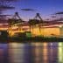 Cargo ship docked at a port with cranes and containers during a sunset. - Olive Oil Times