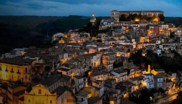 Aerial view of a historic Italian town illuminated at night with buildings and streets visible. - Olive Oil Times