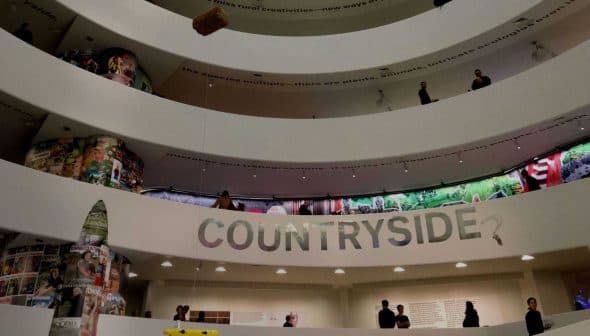 Interior view of a multi-level exhibition space with a large 'COUNTRYSIDE?' sign and visitors on different levels. - Olive Oil Times