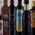 A collection of olive oil bottles with distinct labels and designs arranged in a row. - Olive Oil Times