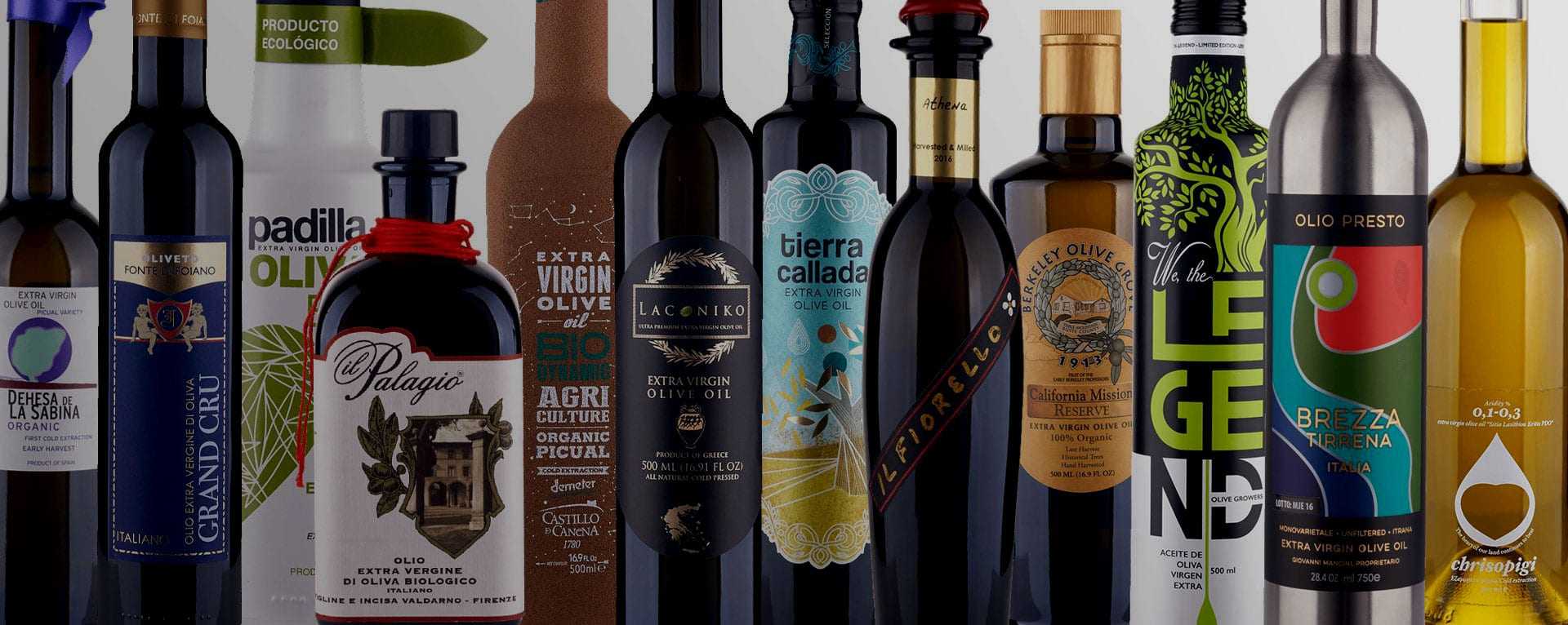 A collection of olive oil bottles with distinct labels and designs arranged in a row. - Olive Oil Times