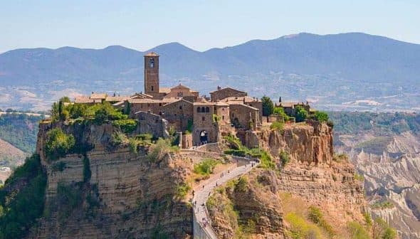 Aerial view of Civita di Bagnoregio, an ancient hilltop village in Italy, surrounded by mountains and valleys. - Olive Oil Times