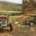 Blue agricultural tractor parked on a dirt path in a field with trees in the background. - Olive Oil Times