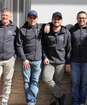 Six men standing in a row wearing gray hoodies with 'TRE Olive' printed on them. - Olive Oil Times