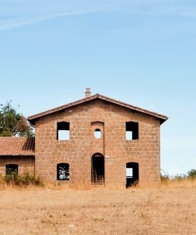 Abandoned stone building with multiple windows and a roof, set against a clear sky. - Olive Oil Times