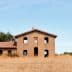 Abandoned stone building with multiple windows and a roof, set against a clear sky. - Olive Oil Times