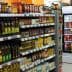 A grocery store aisle displaying various bottles of condiments and cooking oils on shelves. - Olive Oil Times
