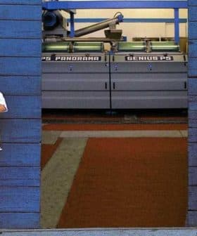 Two individuals standing in a doorway at Tuscus mill, with machinery visible in the background. - Olive Oil Times