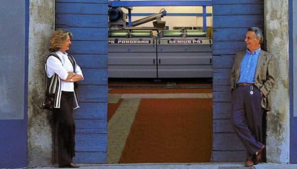 Two individuals standing in a doorway at Tuscus mill, with machinery visible in the background. - Olive Oil Times