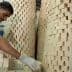 A man wearing gloves stacking rectangular soap blocks in a workshop environment. - Olive Oil Times