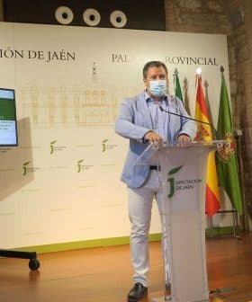 Man speaking at a podium during a press conference at Diputación de Jaén with a screen in the background. - Olive Oil Times