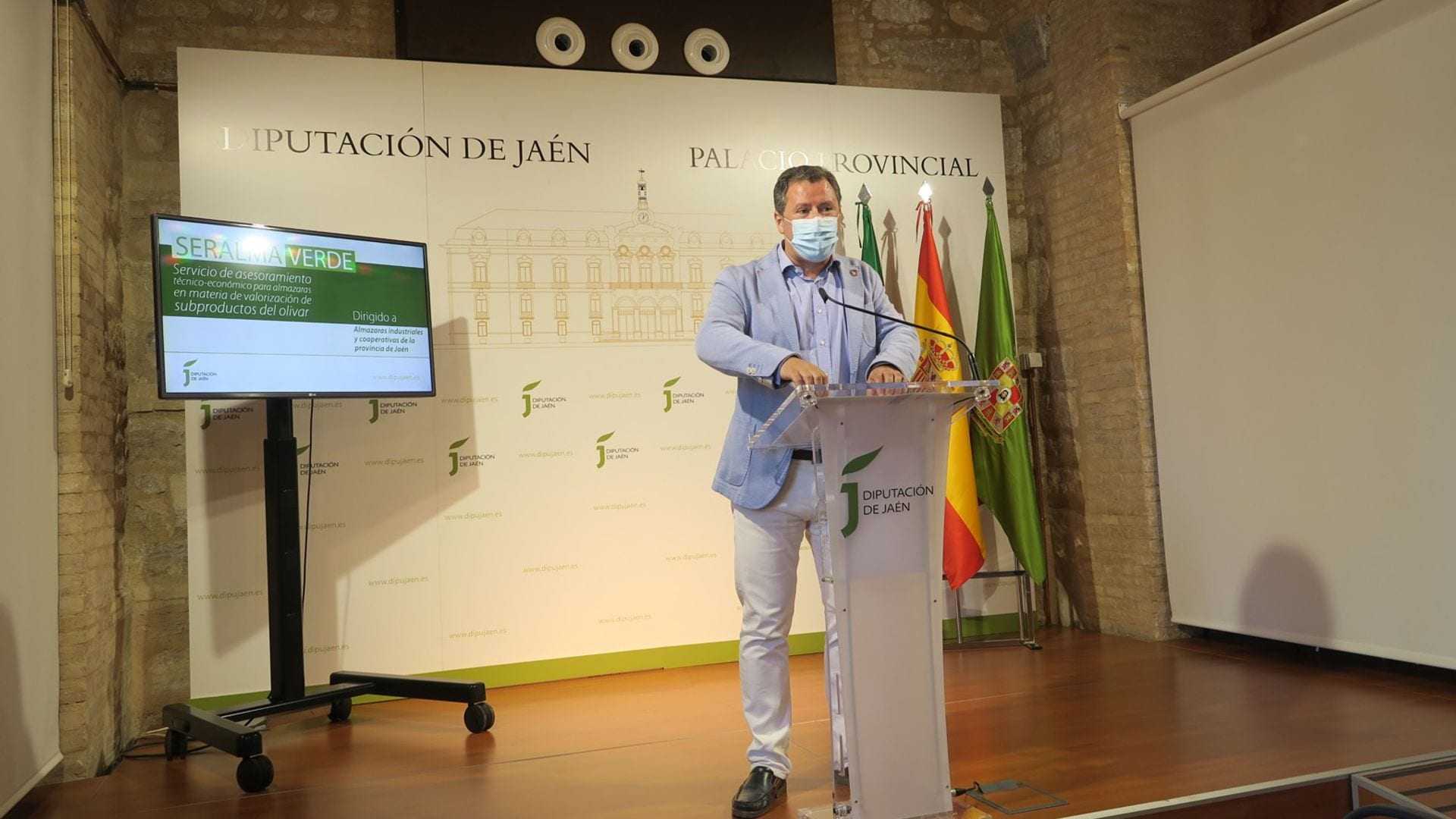 Man speaking at a podium during a press conference at Diputación de Jaén with a screen in the background. - Olive Oil Times