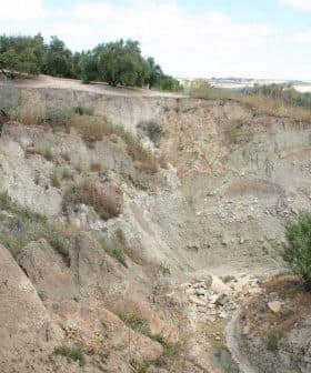 Eroded landscape featuring rocky terrain and sparse vegetation in a dry area. - Olive Oil Times
