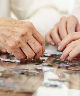 Two hands working together to assemble pieces of a jigsaw puzzle on a table. - Olive Oil Times