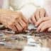Two hands working together to assemble pieces of a jigsaw puzzle on a table. - Olive Oil Times
