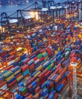 Aerial view of a shipping port filled with colorful containers and cranes at night. - Olive Oil Times