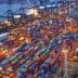 Aerial view of a shipping port filled with colorful containers and cranes at night. - Olive Oil Times