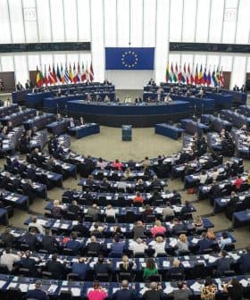 Interior view of the European Parliament in session with members seated in a circular arrangement. - Olive Oil Times