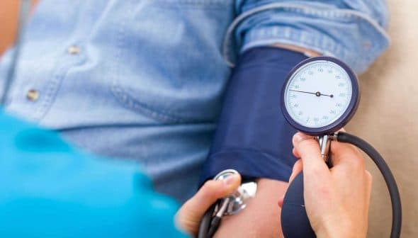A healthcare professional measuring blood pressure using a sphygmomanometer on a patient's arm. - Olive Oil Times