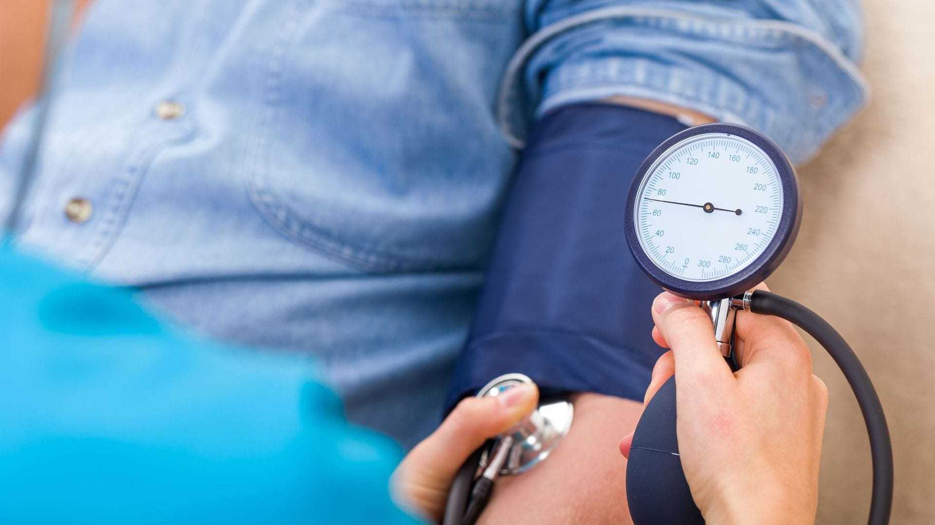 A healthcare professional measuring blood pressure using a sphygmomanometer on a patient's arm. - Olive Oil Times